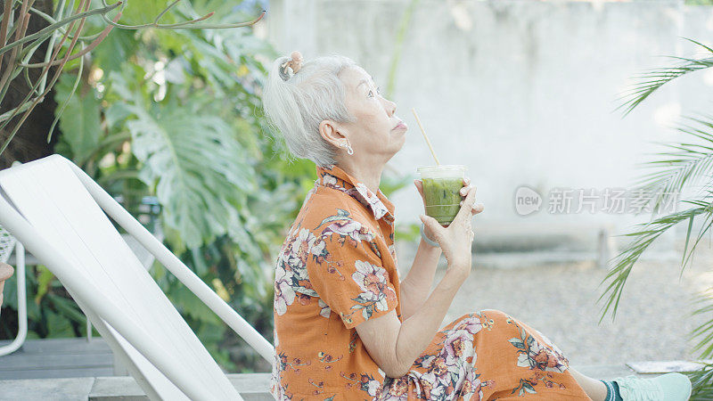 Asian senior woman drinking green tea in outdoor café, young at heart cool attitude